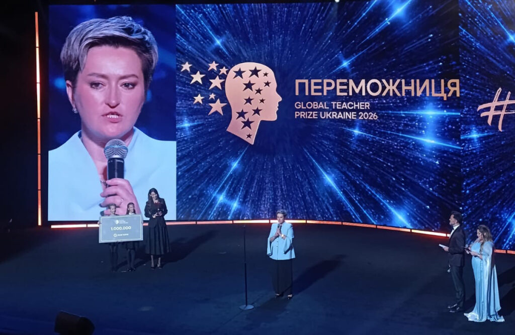 Переможниця премії Global Teacher Prize Ukraine 2026 Світлана Меркулова стоїть у центрі сцени Національної опери України, а позаду неї на великому екрані транслюється її портрет із мікрофоном та напис «ПЕРЕМОЖНИЦЯ GLOBAL TEACHER PRIZE UKRAINE 2026».